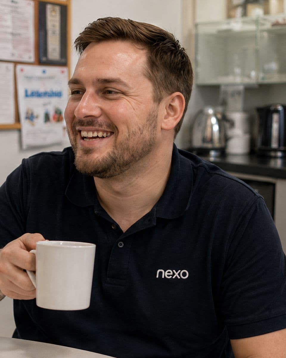 Smiling Nexo care worker in a navy uniform holding a mug of tea in a staff kitchen